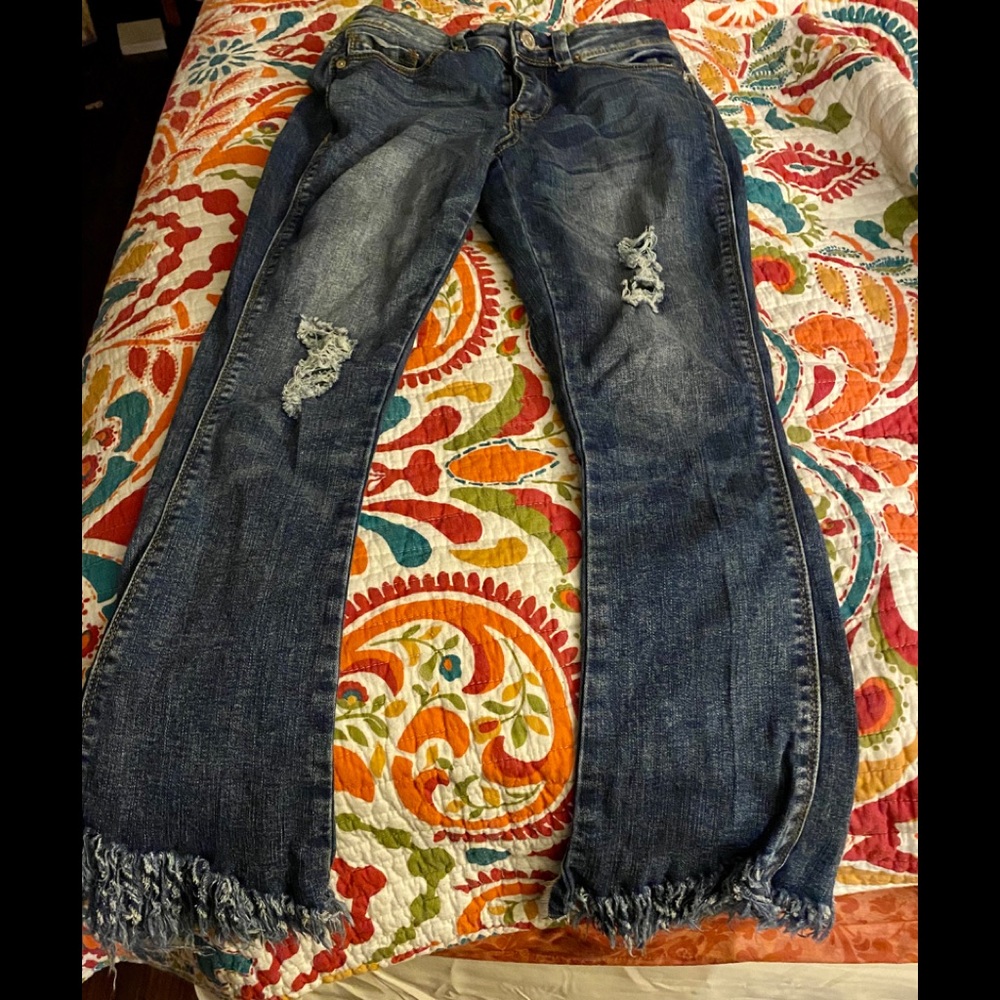 Denim jeans with raveling pants legs.